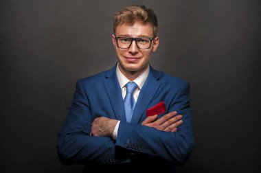 Koyu arka plan üzerinde gülümseyen mavi elbiseli genç yakışıklı adam