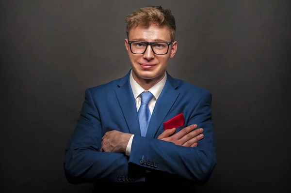 Jovem homem bonito de terno azul sorrindo no fundo escuro — Fotografia de Stock