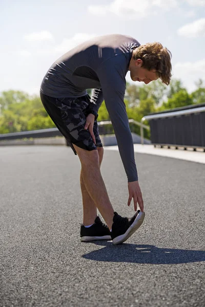 Joven hombre en forma calentándose para correr en la ciudad —  Fotos de Stock