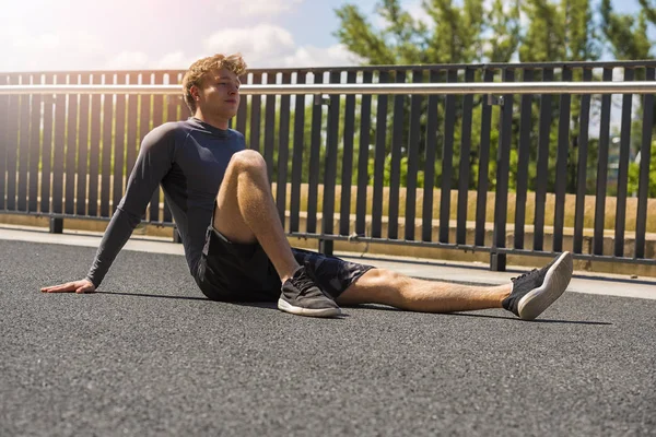 Uitgeput man rust na het joggen in de volle zon — Stockfoto