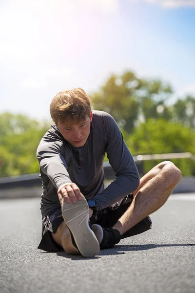Joven hombre en forma calentándose para correr en la ciudad — Foto de Stock