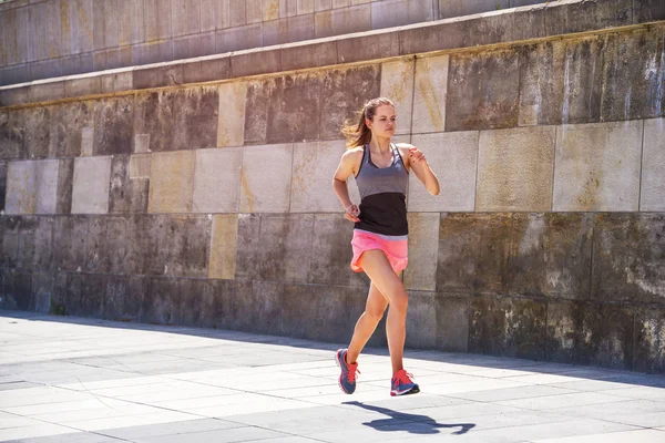 Jeune femme sportive courant sur le trottoir à la lumière du soleil. Inconvénients — Photo