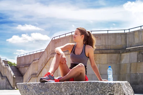 Joven hembra sonriente descansando después de un entrenamiento activo con agua — Foto de Stock