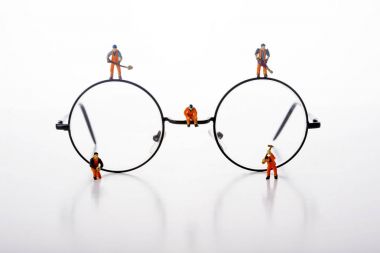 Minyatür insanlar işçiler tarafından gözlük beyaz arka plan üzerinde yürümek..