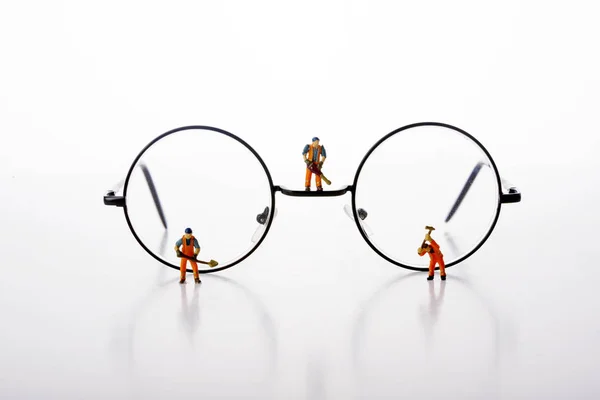 Trabajadores en miniatura caminan por gafas sobre fondo blanco . —  Fotos de Stock