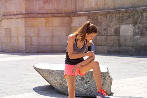 Deportiva mujer tocando la pantalla del teléfono en el brazo banda deportiva antes de runn —  Fotos de Stock