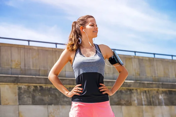 Retrato de mujer joven mirar al lado, de pie al aire libre con auriculares — Foto de Stock