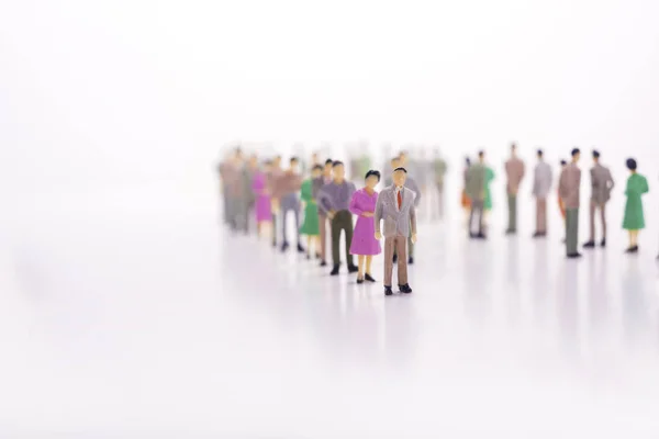 Group of miniature people over white background standing in line — Stock Photo, Image