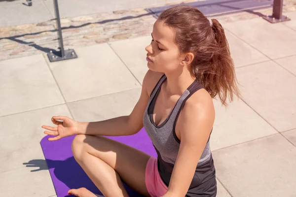 Mujer joven haciendo yoga posición de loto en la ciudad junto al río , Imágenes de stock libres de derechos