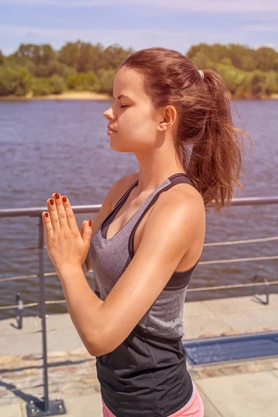 Mujer joven meditando en la ciudad junto al río en verano, cerrado ey Fotos de stock