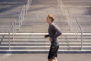 Genç adam şehirde runnin gri renkte spor giyim, koşu