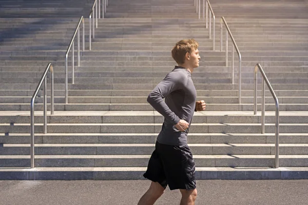 Joven corredor en la ciudad en ropa deportiva en color gris runnin Imagen de archivo