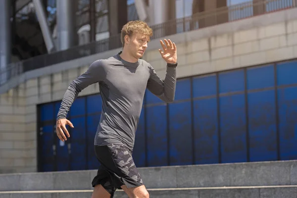 Joven hombre joggong en la ciudad en ropa deportiva en color gris runnin Imágenes de stock libres de derechos