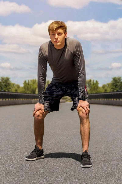 Joven descansando después de hacer ejercicio en el día soleado sobre el cielo con clo — Foto de Stock