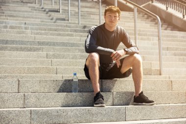 Genç açık, eğitimden sonra dinlenme adam şehirde tam güneş ışığında siting yerleştirmek.