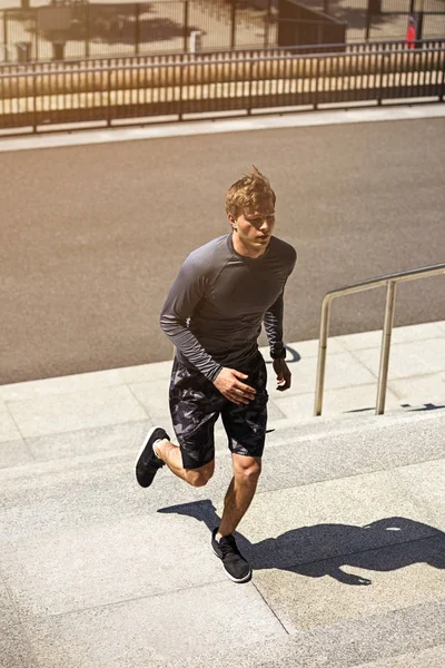 男性アスリートのトレーニングやワークアウト屋外階段をジョギングしながらスポーティな シャツでスポーティな若い男 速度で階段を実行している太陽フレア — ストック写真