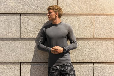 Kas yapı genç atlet açık havada, atletik jogger parlak spor giyim güzel beton duvar arka planda, fitness kavramı çalıştırdıktan sonra dinlenme içinde eğitim sonra yorgun görünüyorsun bir yana,