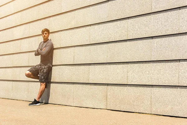 Male jogger resting after morning run while standing against wall background with copy space area for your text message or advertising, young fit men taking break between training outdoors