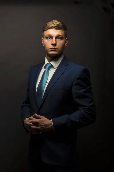 Businessman in suit over dark background portrait. — Stock Photo, Image