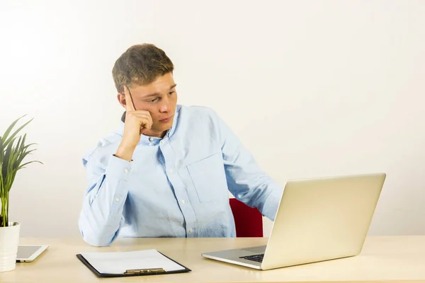 Trabajador masculino en la oficina que trabaja y que piensa, mirando en el ordenador portátil co Fotos de stock libres de derechos