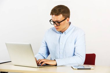 Mutlu genç işadamı onun Ofis Masası dizüstü bilgisayar kullanarak ve bilgisayar, gözlük kullanıyor.