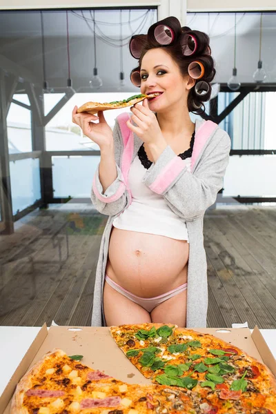 Жінка на кухні їсть піцу — стокове фото