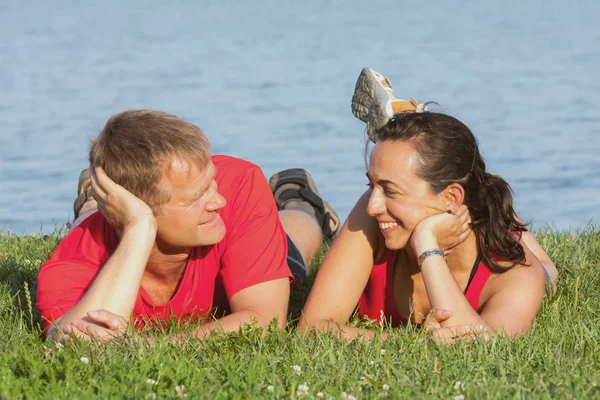Joven pareja alegre se superpone a la orilla del lago — Foto de Stock