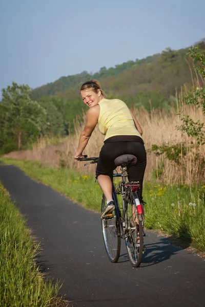 Chica joven y feliz posa delante de la cámara con una bicicleta —  Fotos de Stock