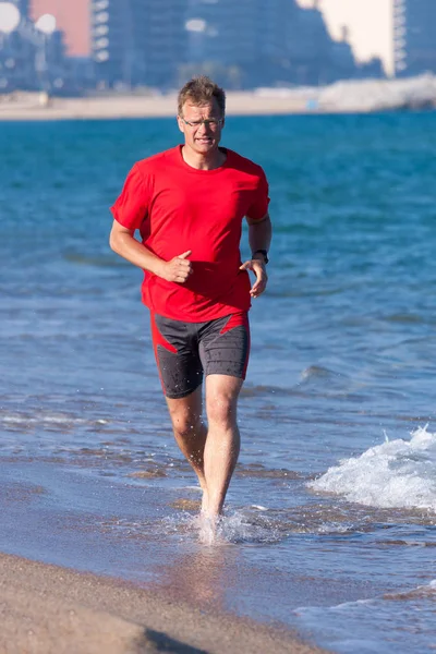 Junger mann läuft am strand von costa brava, spanien — Stockfoto