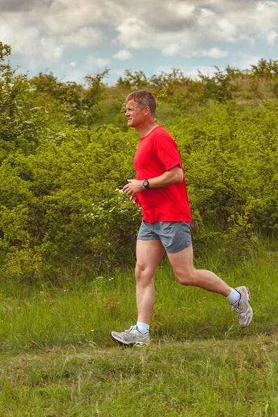 Jeune homme adulte courir sur le terrain en été — Photo