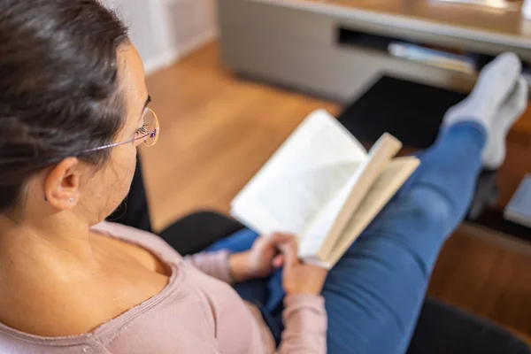 Pretty spanish women reading at home on the sofa — Stock Fotó