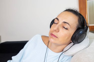 Young Spanish woman listening to music at home with headphones