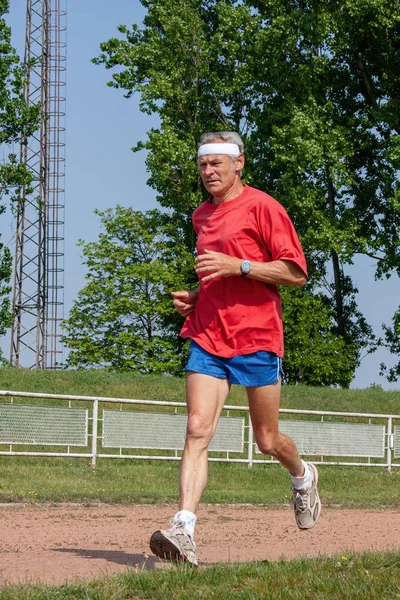 Senior runner running on track and field — Stock Photo, Image