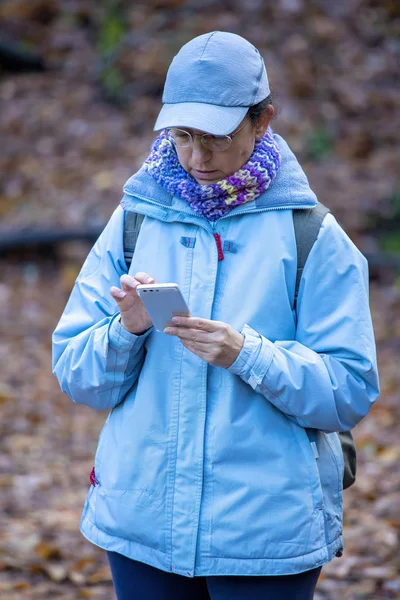 森の中の美しい観光客が携帯電話を見て — ストック写真