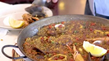 İspanyol restoranında geleneksel bir Akdeniz paella yemeği servis eden bir garson.