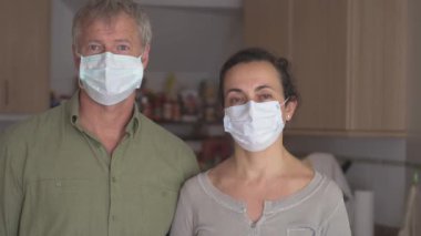Koronavirüs karantinası nedeniyle evde maskeli iki orta yaşlı adam var.