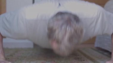 Orta yaşlı bir adam evde şınav çekiyor.