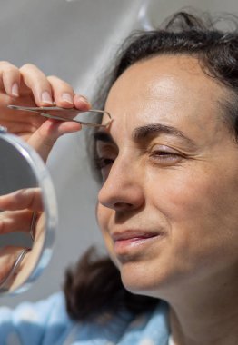 Güzel, genç İspanyol kadın kaşlarını temizliyor.