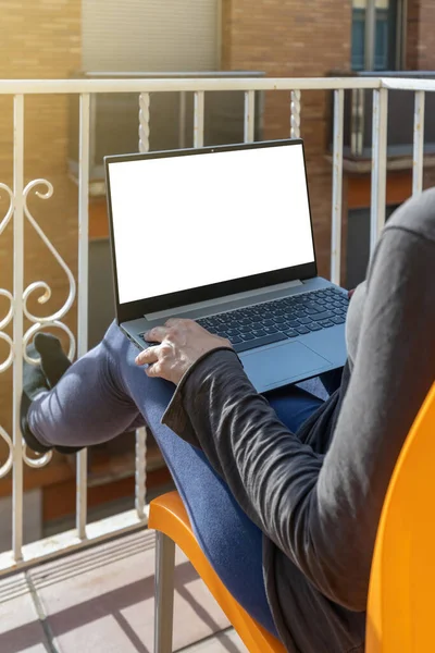 Woman working on laptop on the balcony at home. Home office. White display.