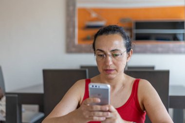 Evde akıllı cep telefonlu güzel bir kadın var.