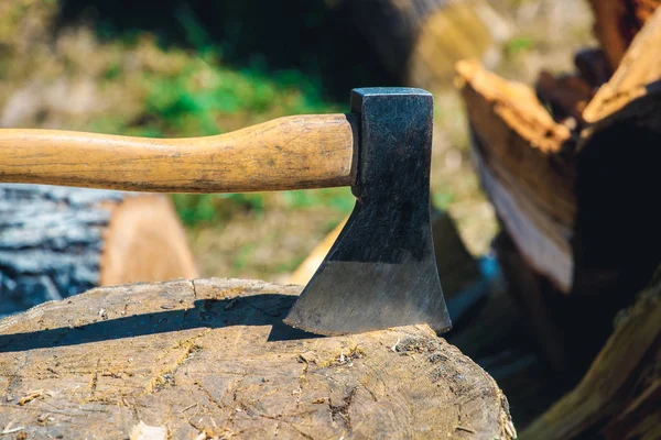 Régi, kopott, karcos, éles ax állva egy fából készült, repedt fatönkön egy apróra vágott fa háttér. — Stock Fotó