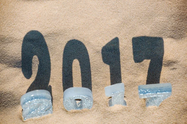 Cuatro figuras de Año Nuevo están en la arena en la playa o junto al mar, proyectan una gran sombra en el suelo. Celebración de Año Nuevo y Navidad en el océano, el mar. Viajar . — Foto de Stock