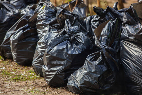 Черные, полные и связанные мешки для мусора, стоящие вместе на улице, на улице. вывоз, сортировка и переработка мусора
.