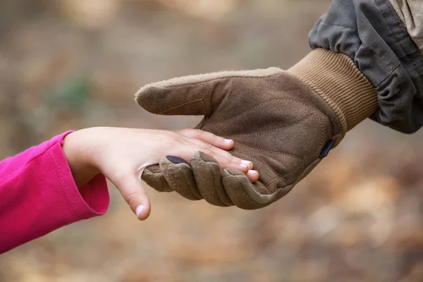 Een soldaat in het leger uniform en handschoenen, stak zijn hand een klein meisje. Close-up. — Stockfoto