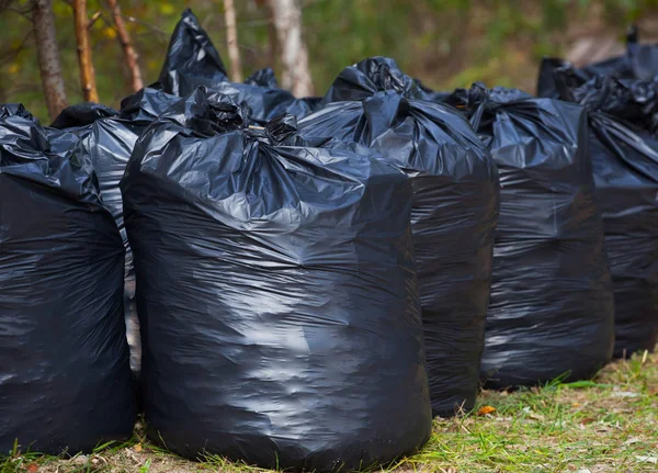 Zwart, volledige en verbonden vuilniszakken, permanent samen op straat, buitenshuis. verwijderen, sorteren en recycleren van afval. — Stockfoto