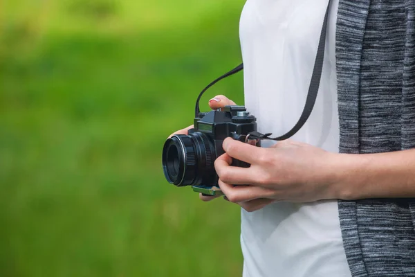 Menina-fotógrafo bonita segura uma câmera e fazer uma foto — Fotografia de Stock