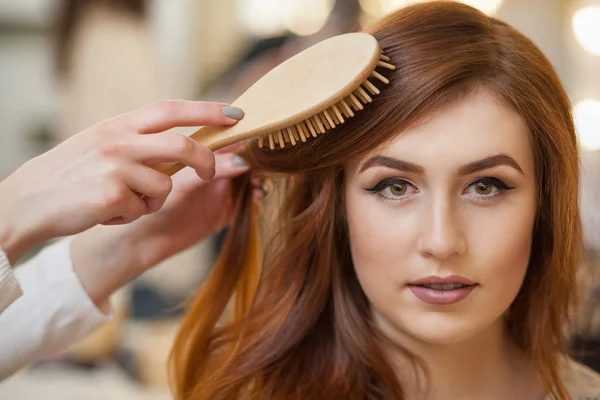 Salon fryzjerski czesanie jej długie, czerwone włosy swojego klienta w salonie piękności — Zdjęcie stockowe