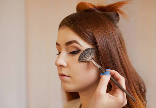 Vizážistka s ruměnec kartáč na obličeji, uzavírá denní make-up v salonu krásy. — Stock fotografie
