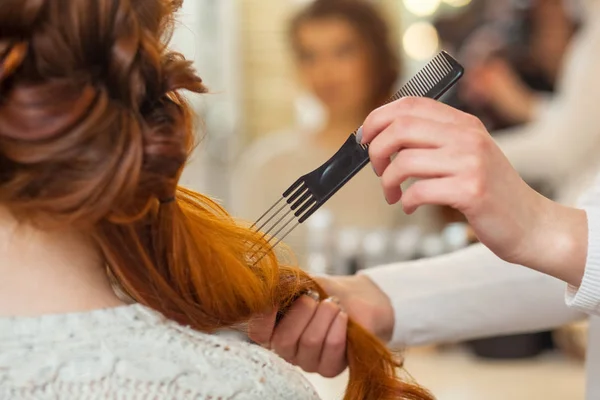 Красивая, рыжая девушка с длинными волосами, парикмахер плетет французскую косу , — стоковое фото