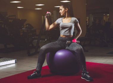 İnce, vücut geliştirmeci kız ağır halter kaldırma, bir egzersiz sırasında uygunluk Topa otur